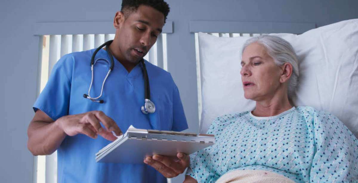 A nurse taking notes at a patient's bedside