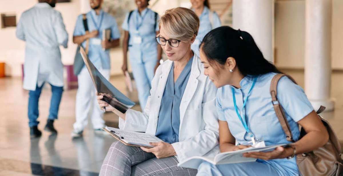 A nursing preceptor mentors an ABSN student in between rounds