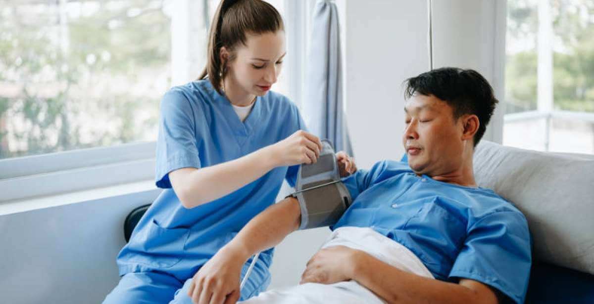 A nurse checking a bedridden patient's blood pressure